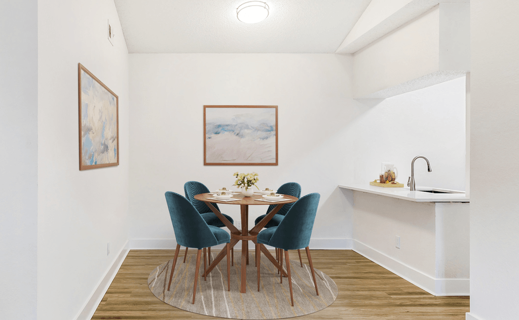 Virtually staged dining room with wood table, green chairs, wood style flooring, accent rug, wall art and white quartz countertop on breakfast bar 